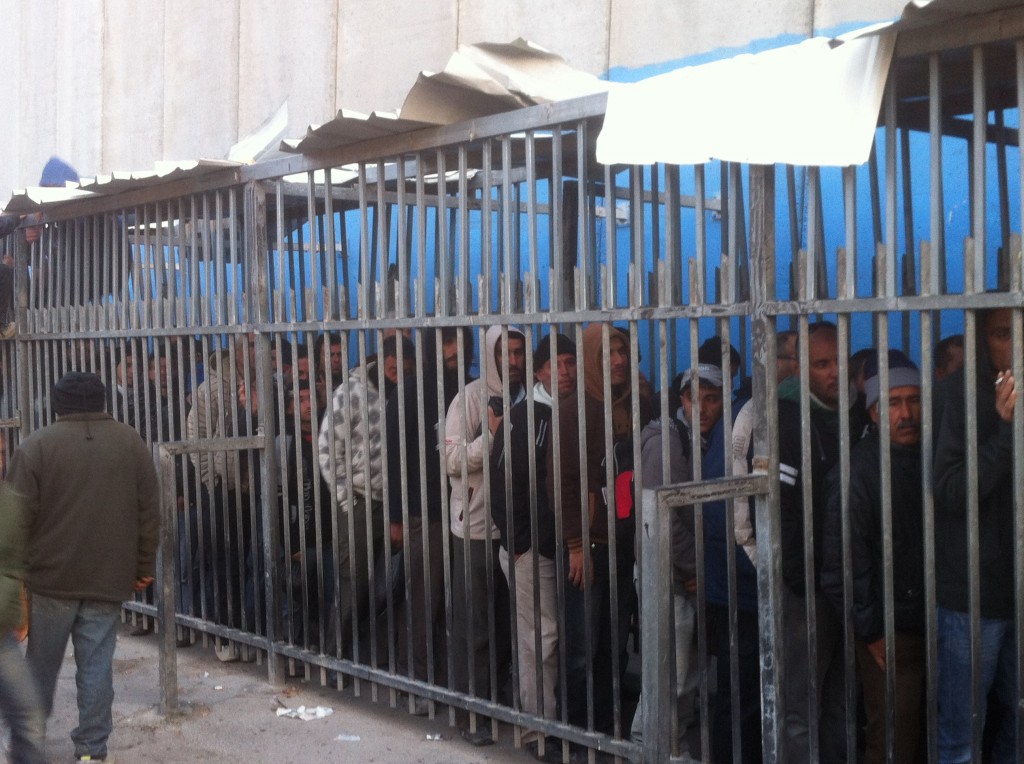 En kö av män bakom galler vid vägspärren Gilo.