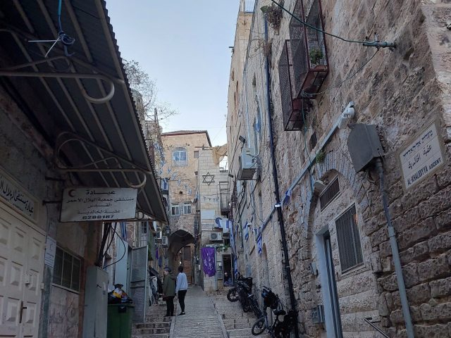 En gränd i gamla stan i Jerusalem, där en israelisk bosättning markeras med davidsstjärnan och israeliska flaggor.