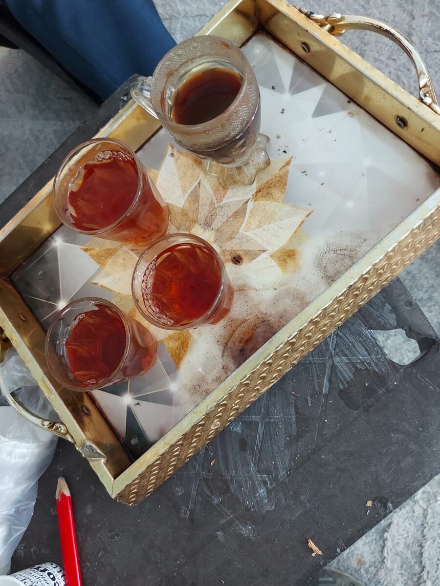 En vacker träbricka med tre glaskoppar med the och en glaskopp med kaffe.